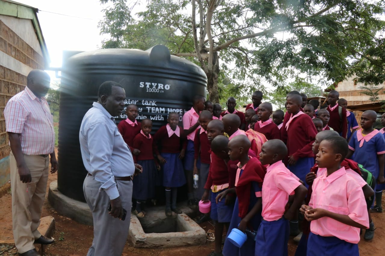 Teachers and students in front of the water tank